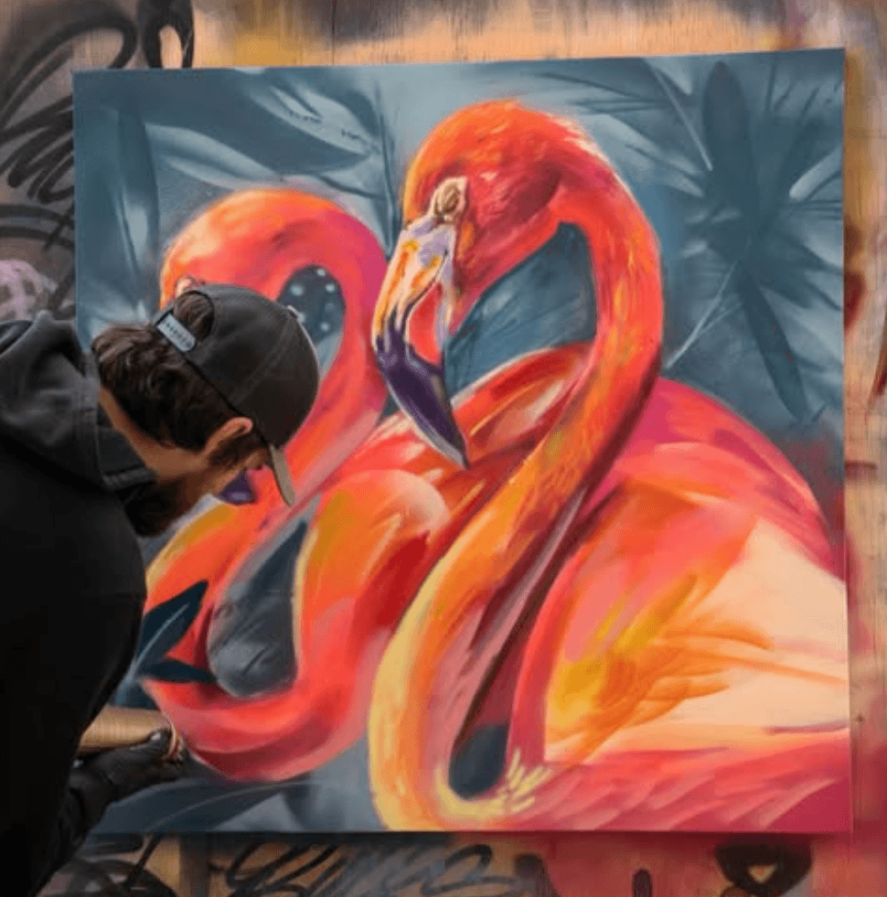 Artist painting a large-scale flamingos mural