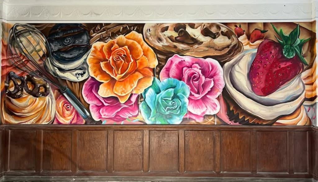 Custom bakery mural painted for Brittany's Cupcake Shoppe featuring cupcakes, desserts, and colorful flowers