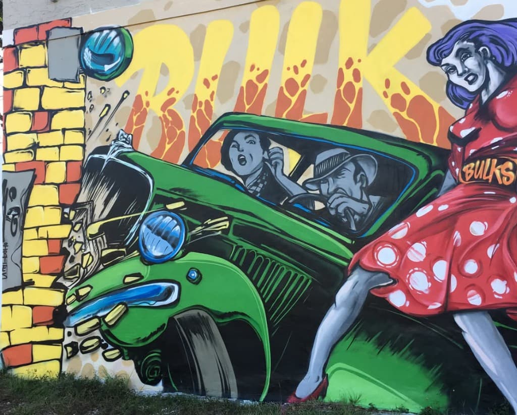 Close up of vintage car crashing through wall in Clematis Street mural on the Respectable Street building in West Palm Beach by Bulk Styles