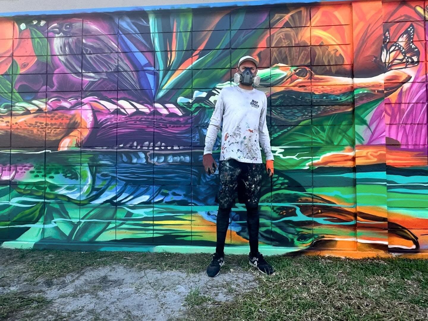 Mark Francis of Bulk Styles standing in front of the completed Clewiston Sugar Festival mural