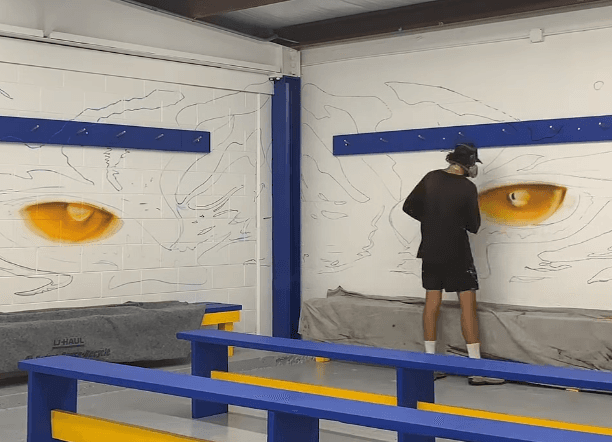Mark Francis of Bulk Styles painting the tiger eyes during the Clewiston Tigers locker room mural installation
