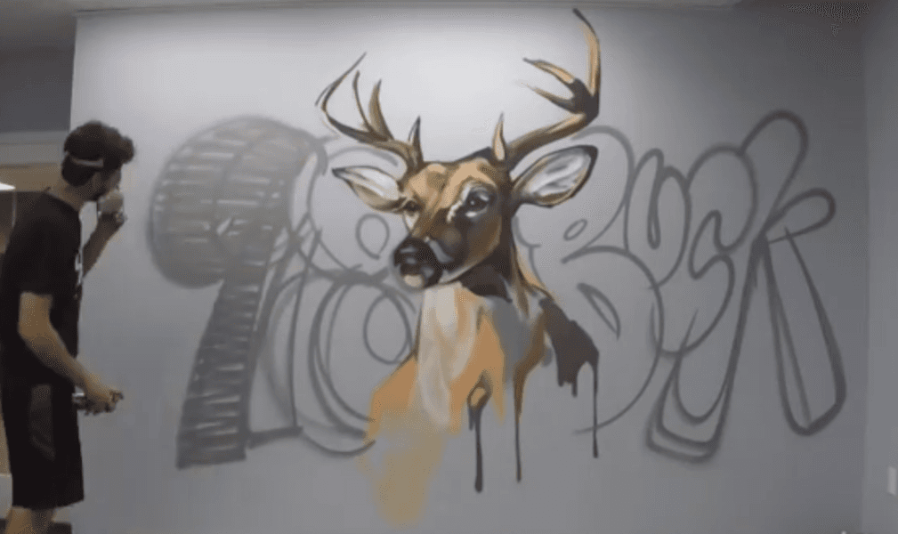 Deer wall mural in progress as a mural artist adds spray paint detail to the artwork