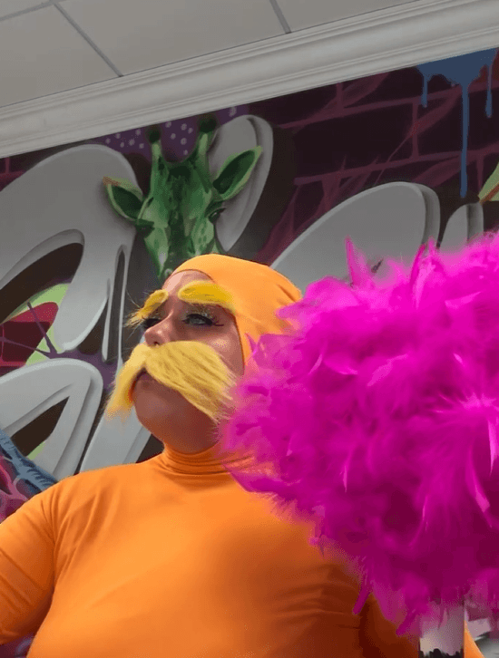 person in costume standing in front of colorful giraffe mural painted by Mark Francis Bulk Styles at Giraffe Media Group office