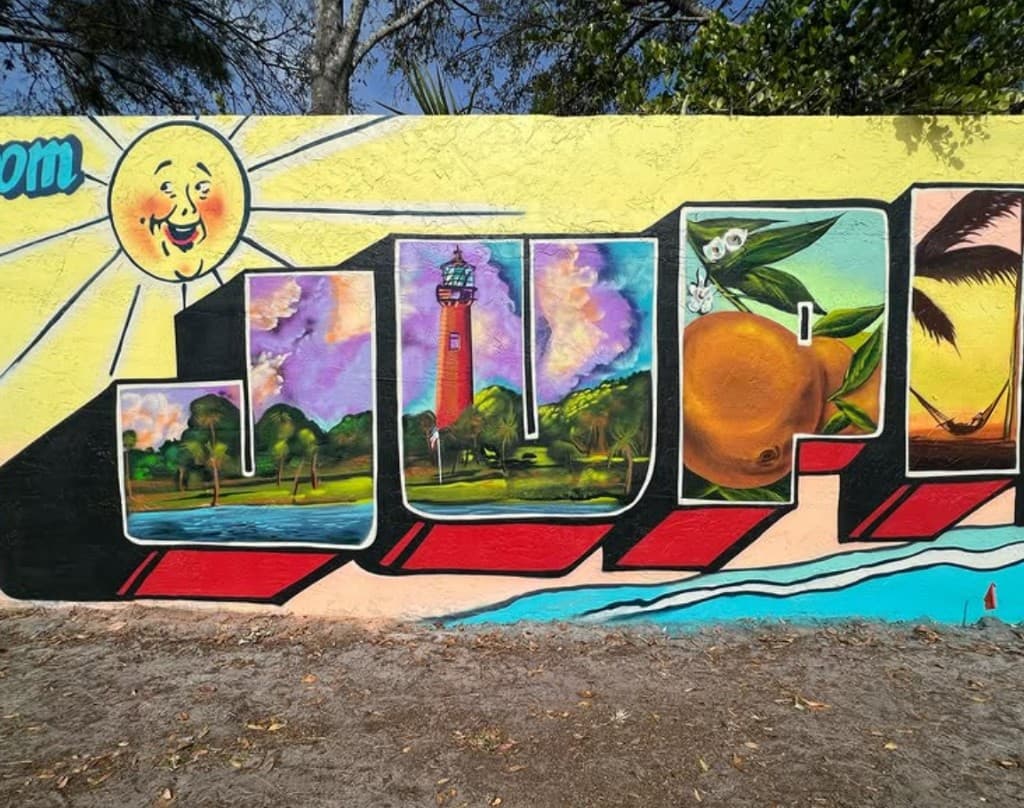 detail of JUP letters in the Greetings From Jupiter postcard style mural featuring Jupiter Lighthouse and orange imagery painted by Mark Francis Bulk Styles