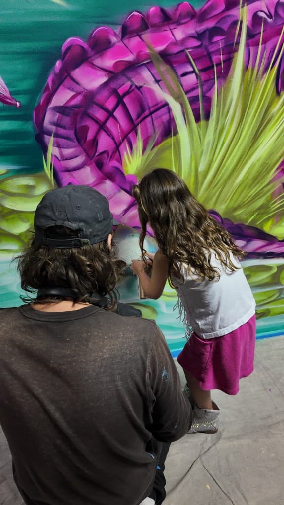 Interactive audience mural painting where guests add color to a collaborative artwork