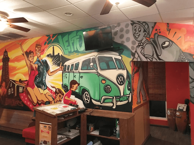 Colorful commercial mural painted on an interior business wall featuring illustrated characters and a vintage van
