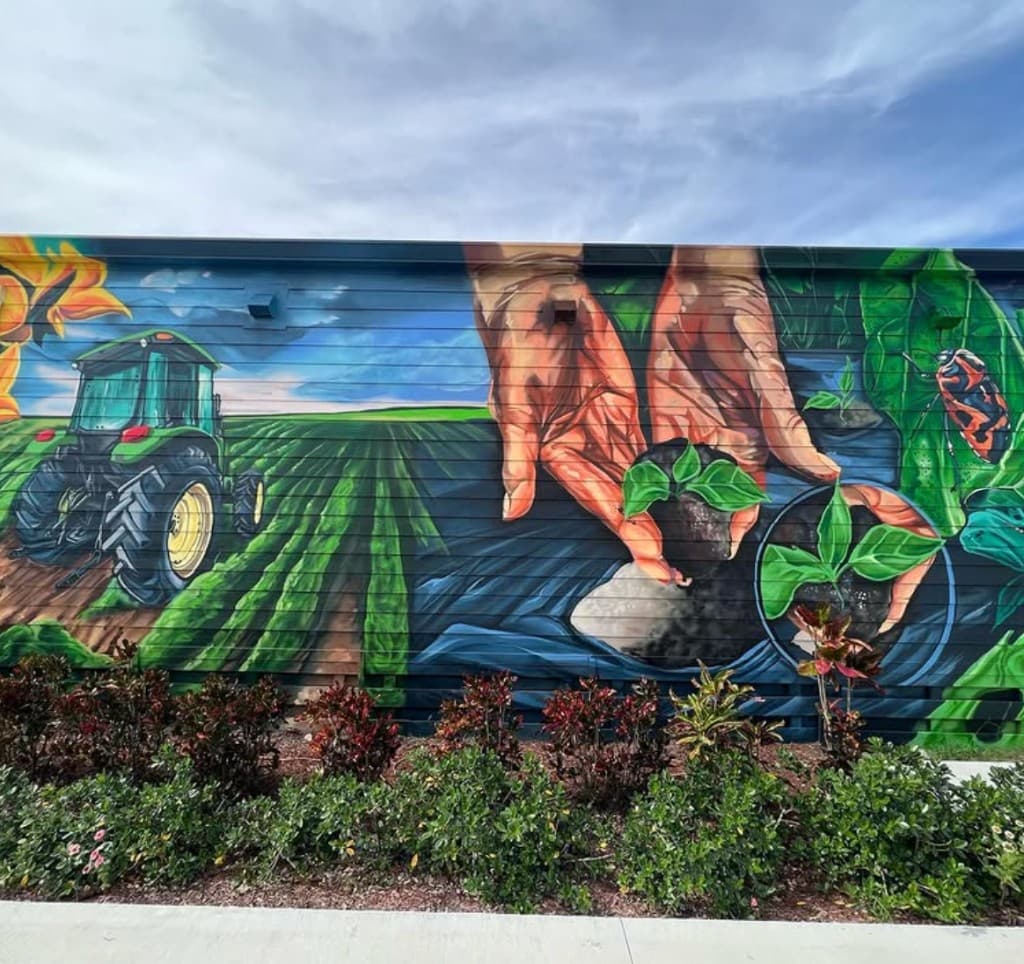 section of Kai Kai Farm agriculture mural showing tractor farmland rows and hands planting seedlings painted by mural artist Mark Francis Bulk Styles