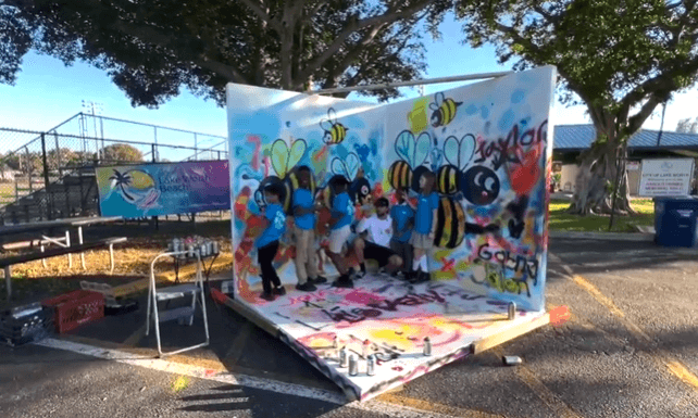 students posing in front of their finished mural during the Lake Worth Beach Street Painting Festival youth art workshop led by mural artist Mark Francis