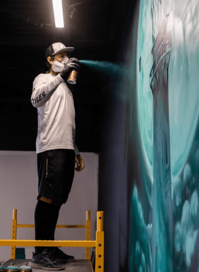 Mural artist Mark Francis (Bulk Styles) spray painting a large scale mural