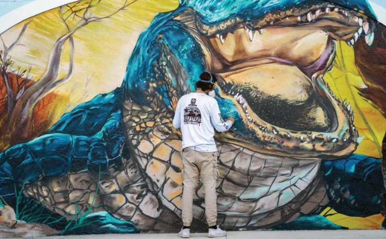 mural artist Mark Francis Bulk Styles painting large alligator mural at Ocean Republic Brewing in Stuart featured in Jupiter Magazine
